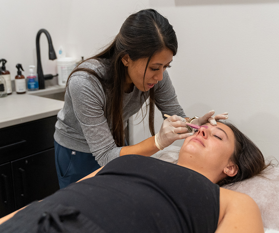 Body wax esthetician performing facial service